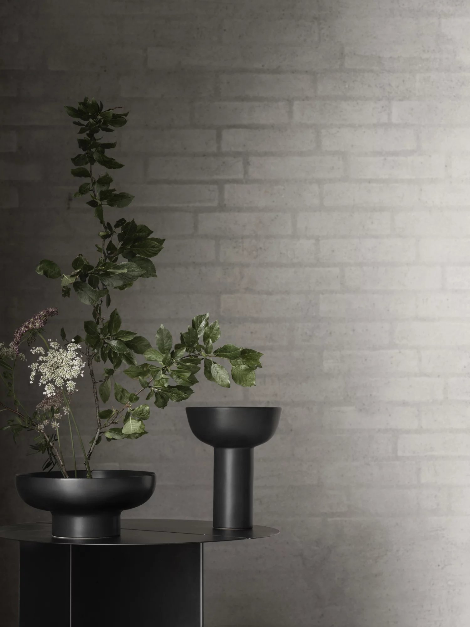Oru Beistelltisch von Blomus in Burned Metal Optik mit Blumen und Dekoration.
