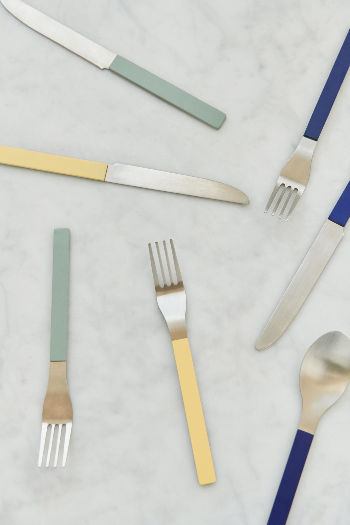MVS Cutlery: Messer, Gabeln und Löffel mit farbigen Griffen in Gelb, Blau und Grün.