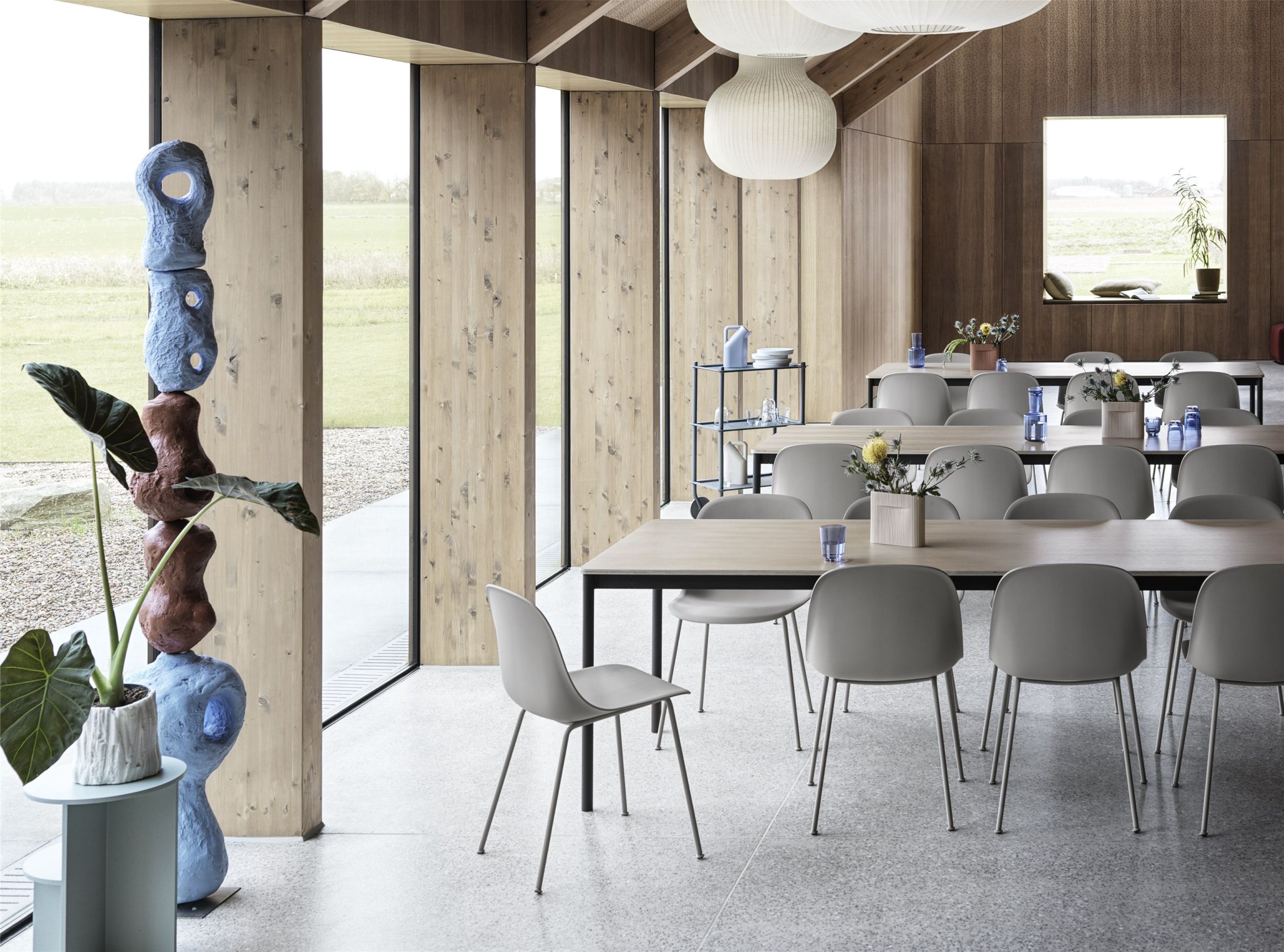Innenaufnahme eines hellen Raumes mit mehreren Fiber Side Chairs von Muuto an Holztischen.