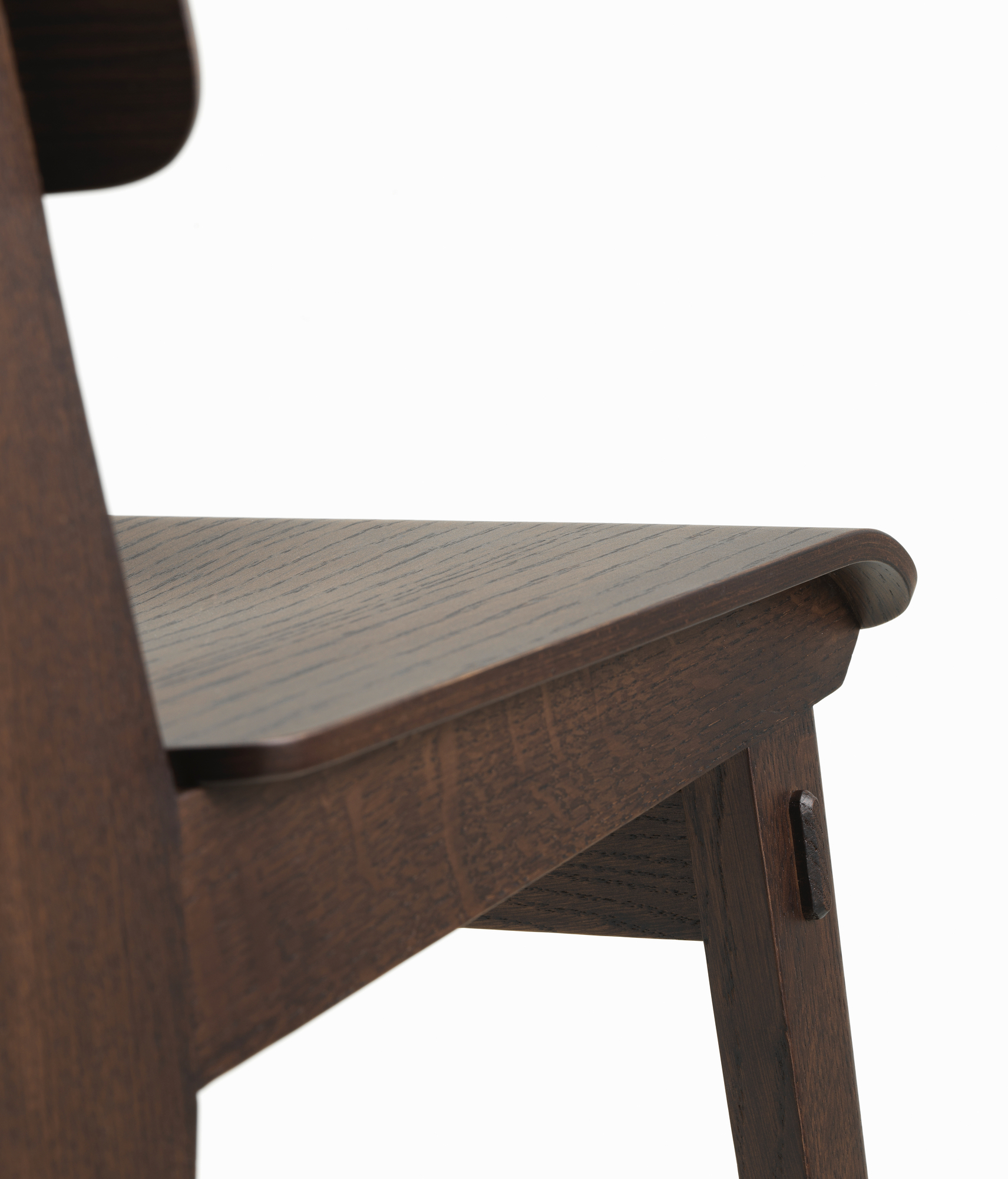 Detailaufnahme des Vitra Chaise Tout Bois Stuhls: Dunkles Holz, Sitzfläche und Stuhlbein mit markanter Holzmaserung.