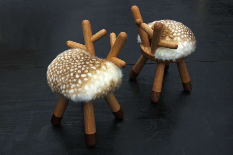 Zwei Bambi Kinderstühle von EO mit Fellimitat und Holzbeinen auf dunklem Boden.