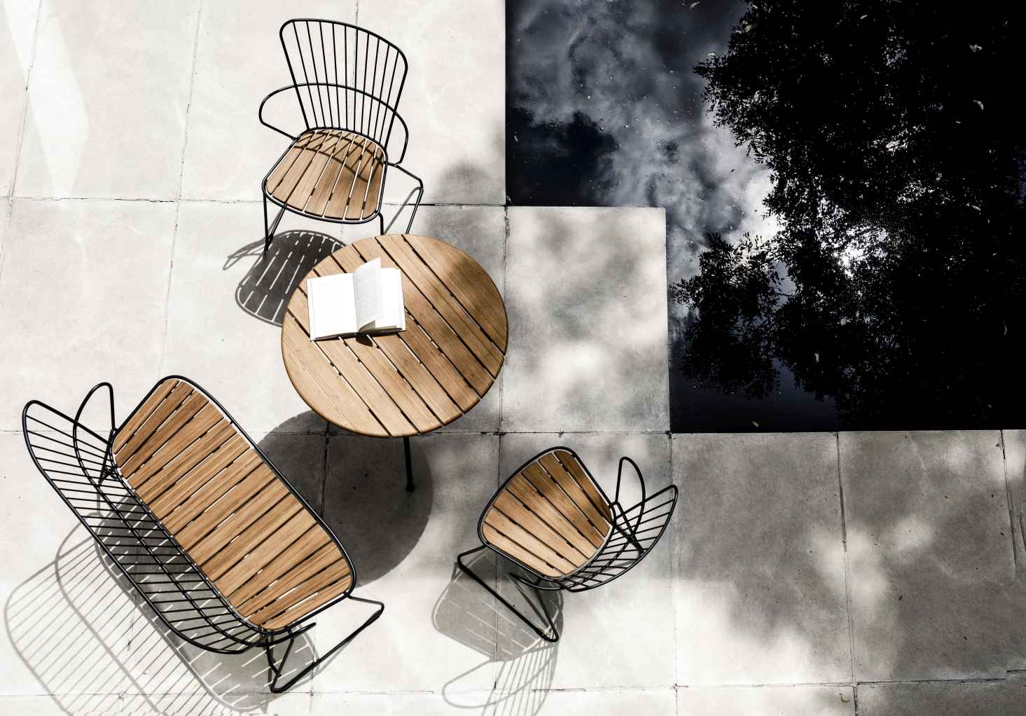 Draufsicht: Houe Circle Outdoor Tisch (Ø 110 cm) mit Stühlen und Buch im Freien.