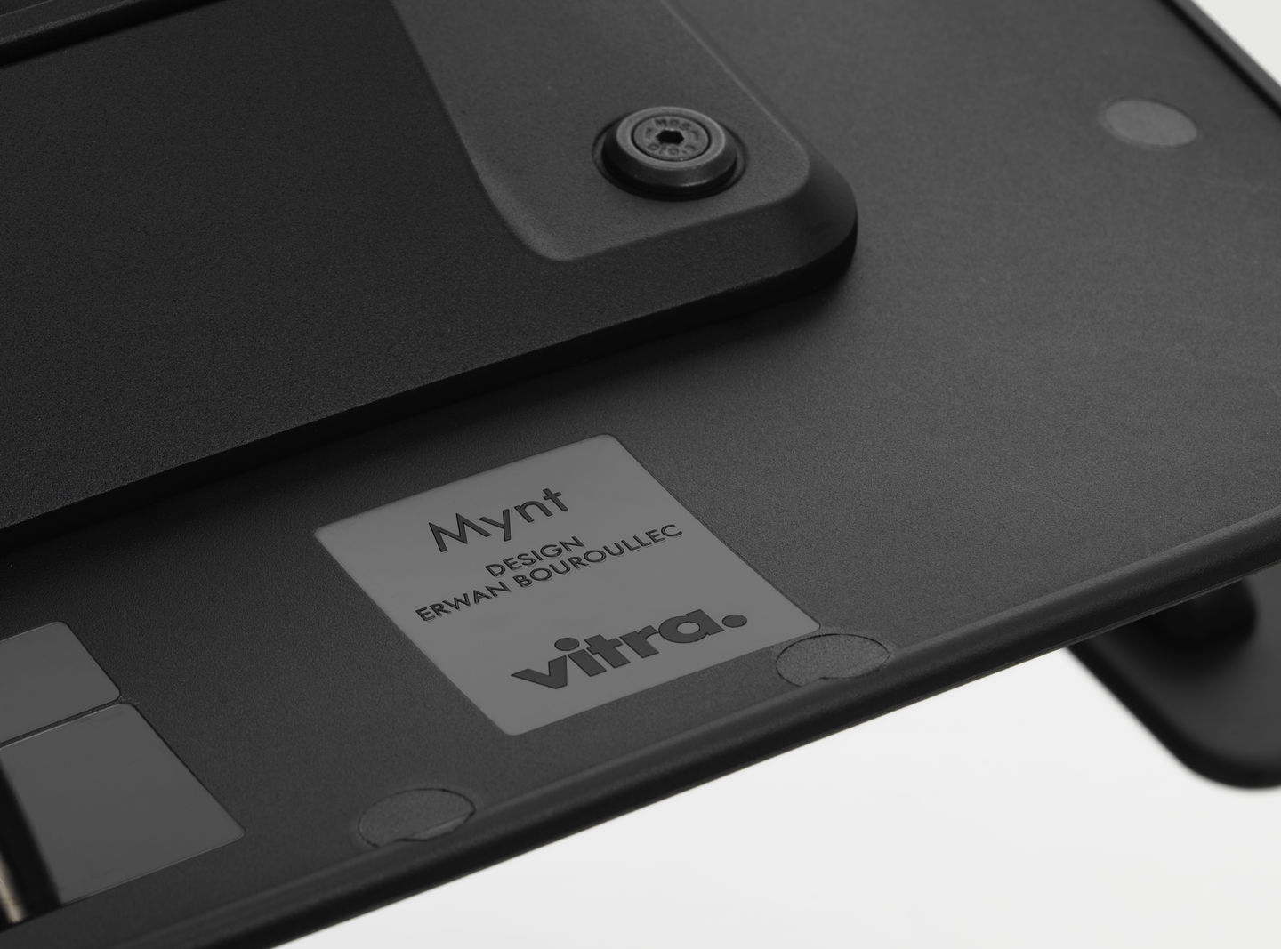 Detailaufnahme der Unterseite eines schwarzen Vitra Mynt Bürostuhls mit Herstellerlogo.