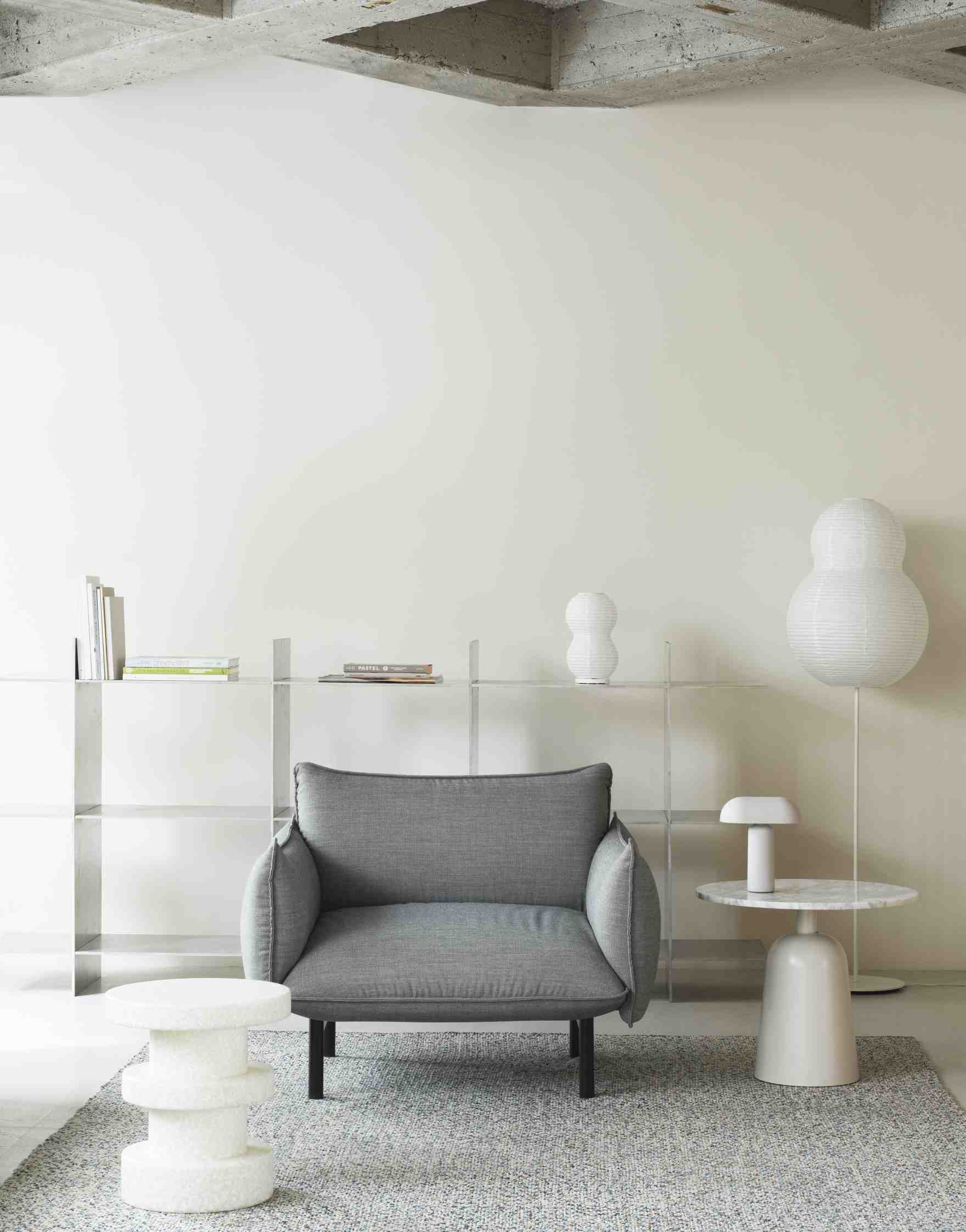 Wohnzimmer-Szene mit grauem Sessel, weißem Regal und Normann Copenhagen Turn Table Marmor Tisch als Beistelltisch.