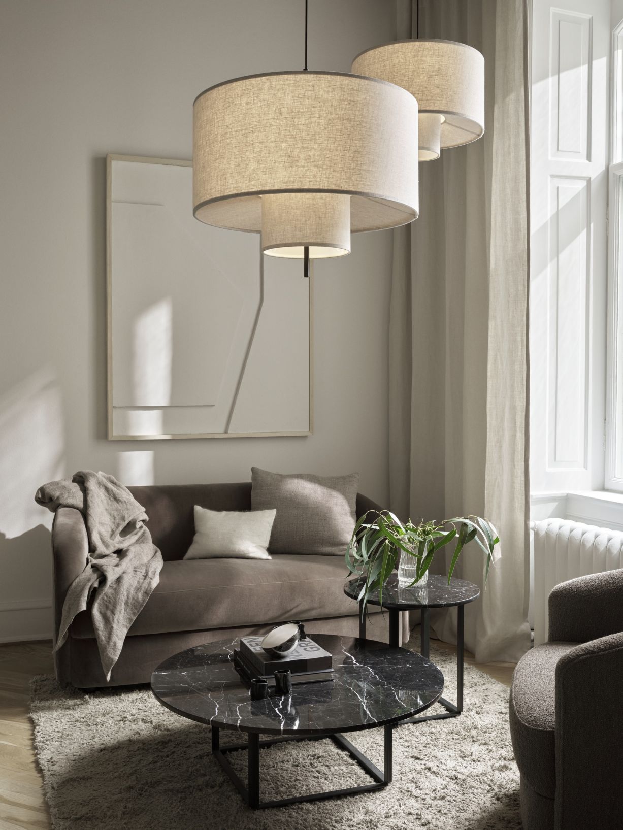 Beige Margin Pendelleuchte von New Works über braunem Sofa in einem modern eingerichteten Wohnzimmer.