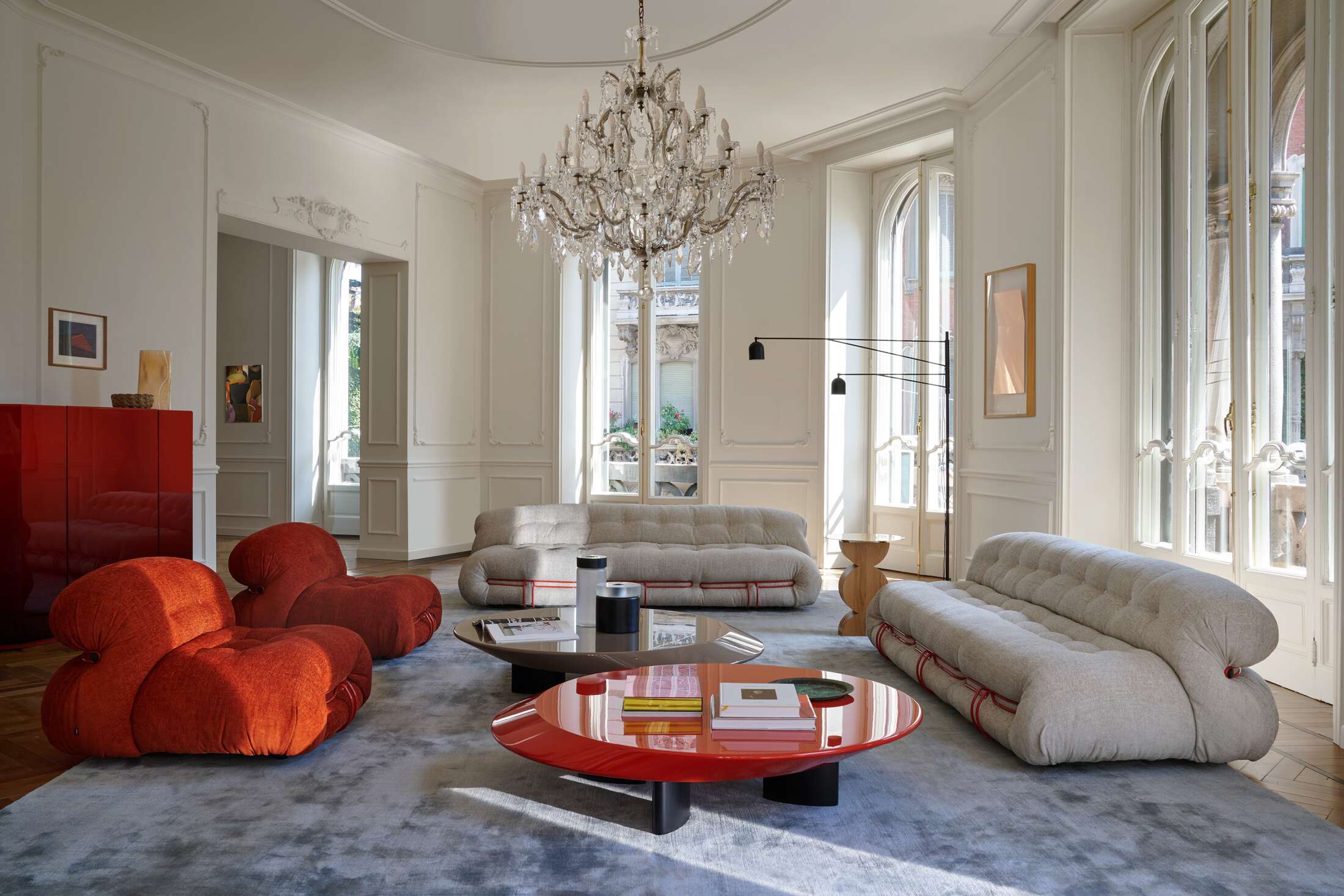 Helles Wohnzimmer mit Cassina Soriana Sofa, Sessel und Couchtischen unter einem Kristalllüster.