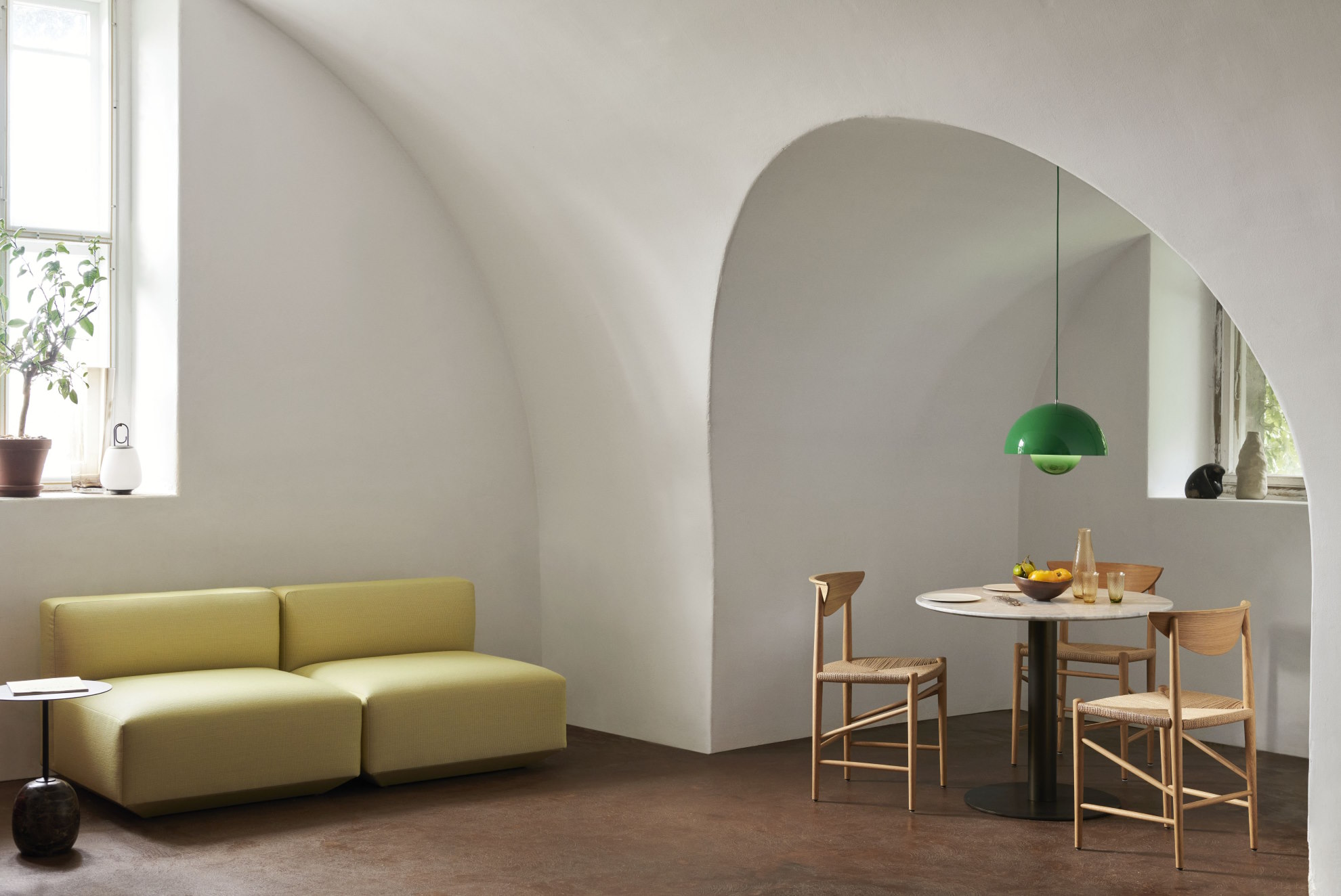Helles Wohnzimmer mit gelbem Sofa, Esstisch mit Holzstühlen und grüner Pendelleuchte. Modernes Möbeldesign.