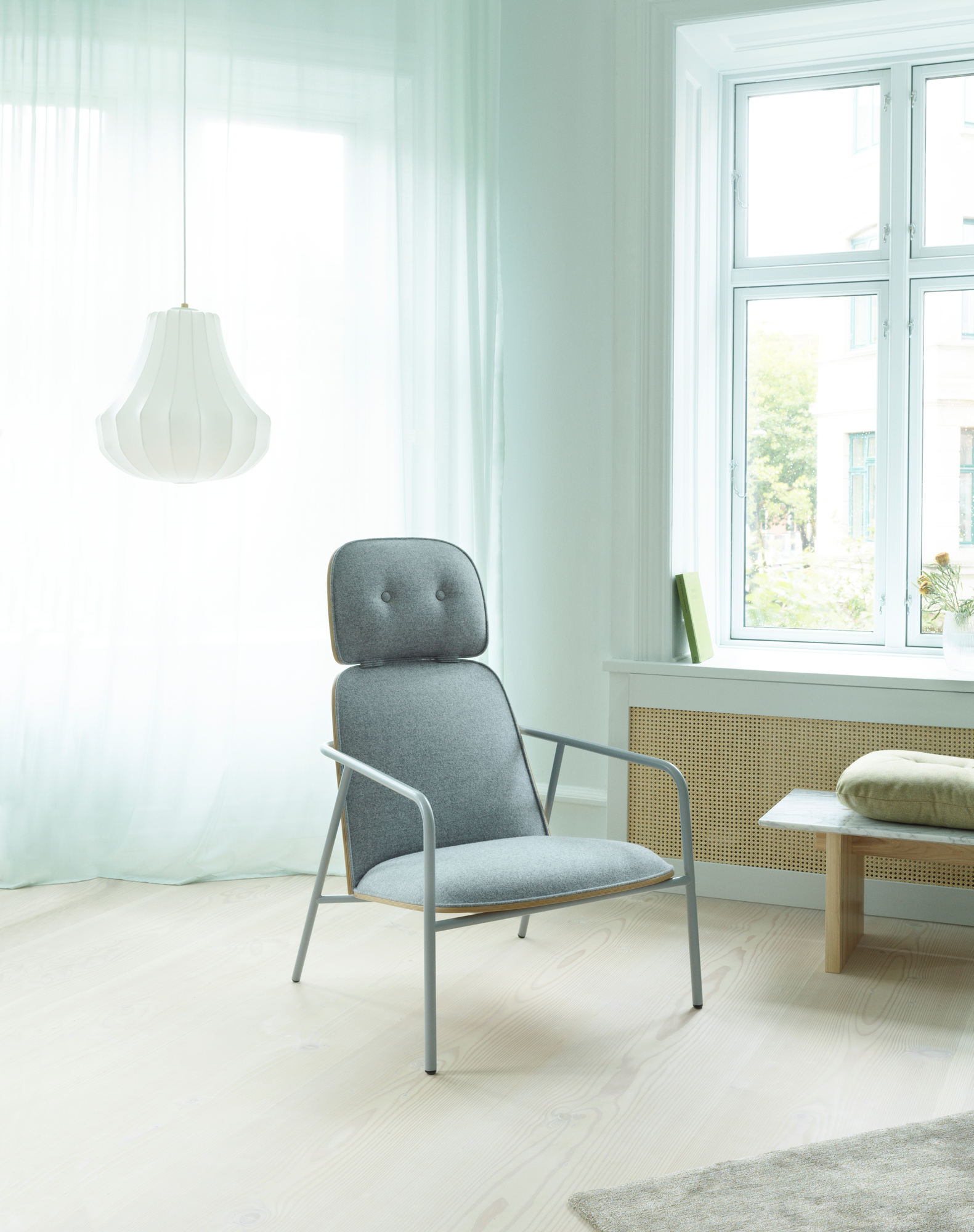 Helle Raumansicht mit Normann Copenhagen Phantom Lampe, grauem Sessel mit Armlehne und Fenster mit Vorhang.