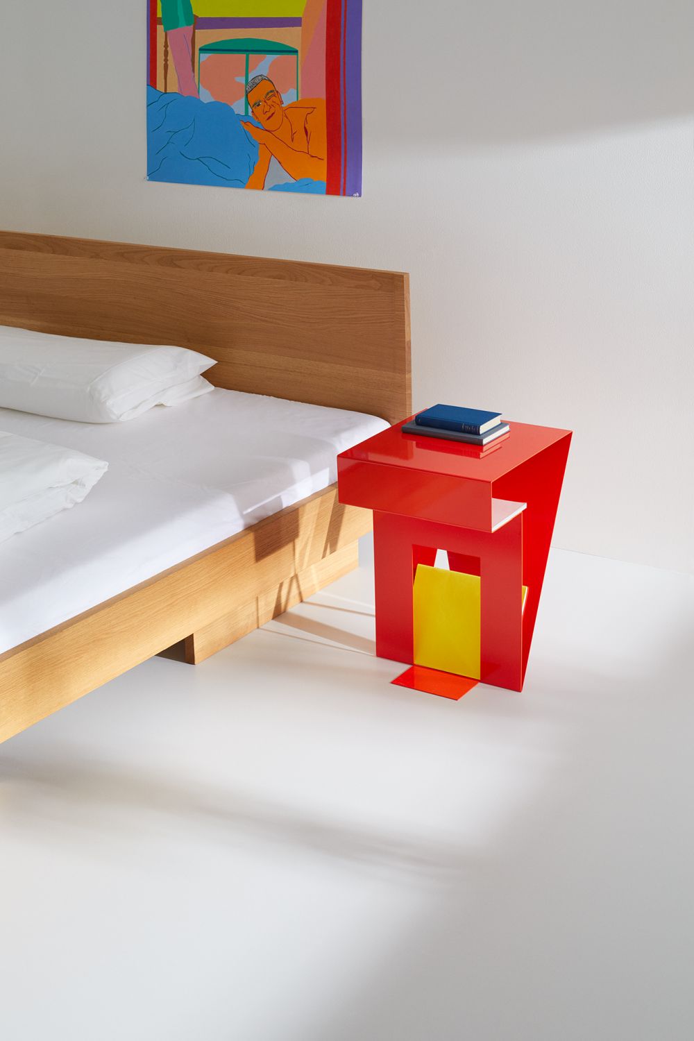 ZIANS Bett Large mit Kopfteil aus Eiche gewachst, mit rotem Nachttisch und Kunstwerk an der Wand.