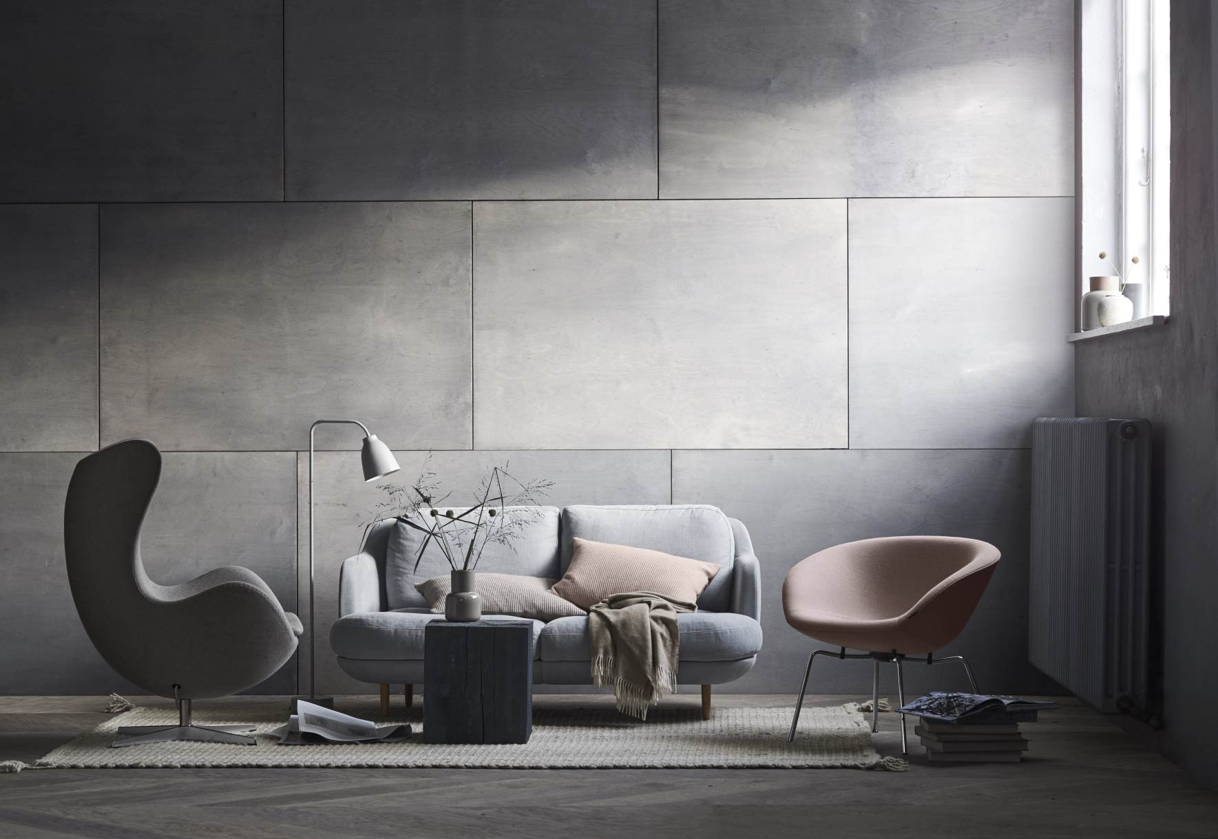 Wohnzimmer Interieur mit grauem Fritz Hansen Pot Sessel, Sofa und Designermöbeln auf einem Teppich.