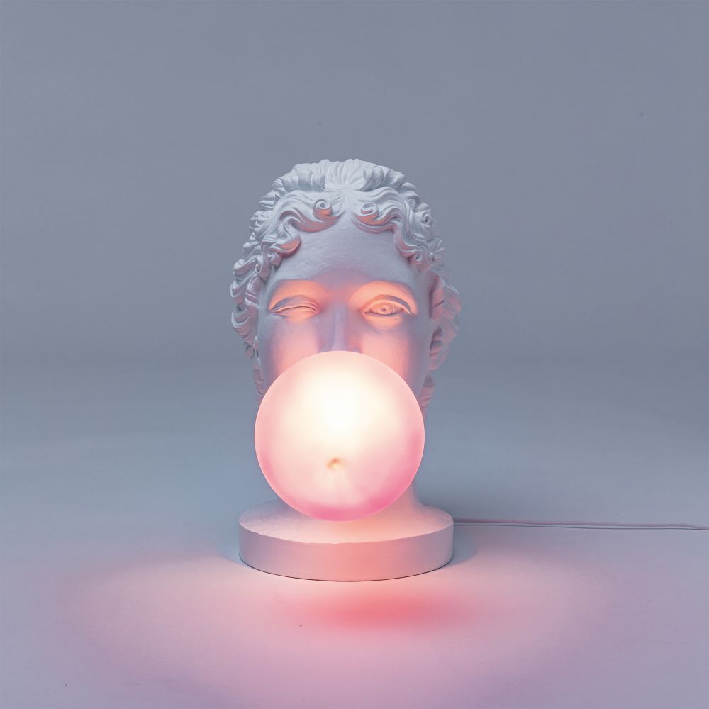 Grace Lamp Tischleuchte von Seletti: Skulptur einer Büste mit rosa leuchtender Kugel als Kaugummi.