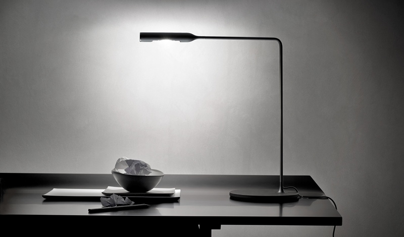Schwarze Flo Desk Tischleuchte Lumina auf einem Schreibtisch, minimalistisches Design mit indirektem Licht.