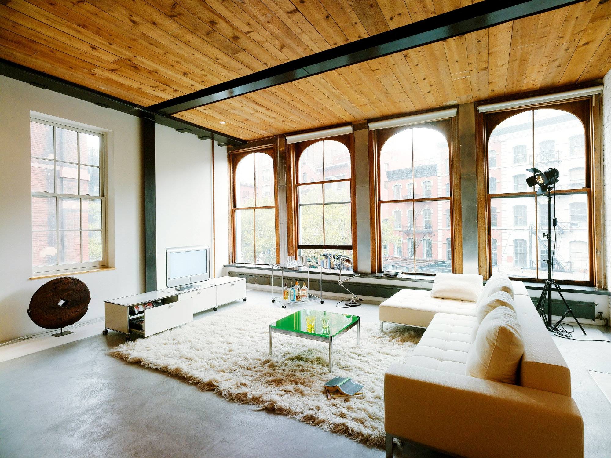 Heller Wohnraum mit USM Haller Couchtisch 75x75 in Grün, weißer Couch, Teppich und großzügigen Fenstern.