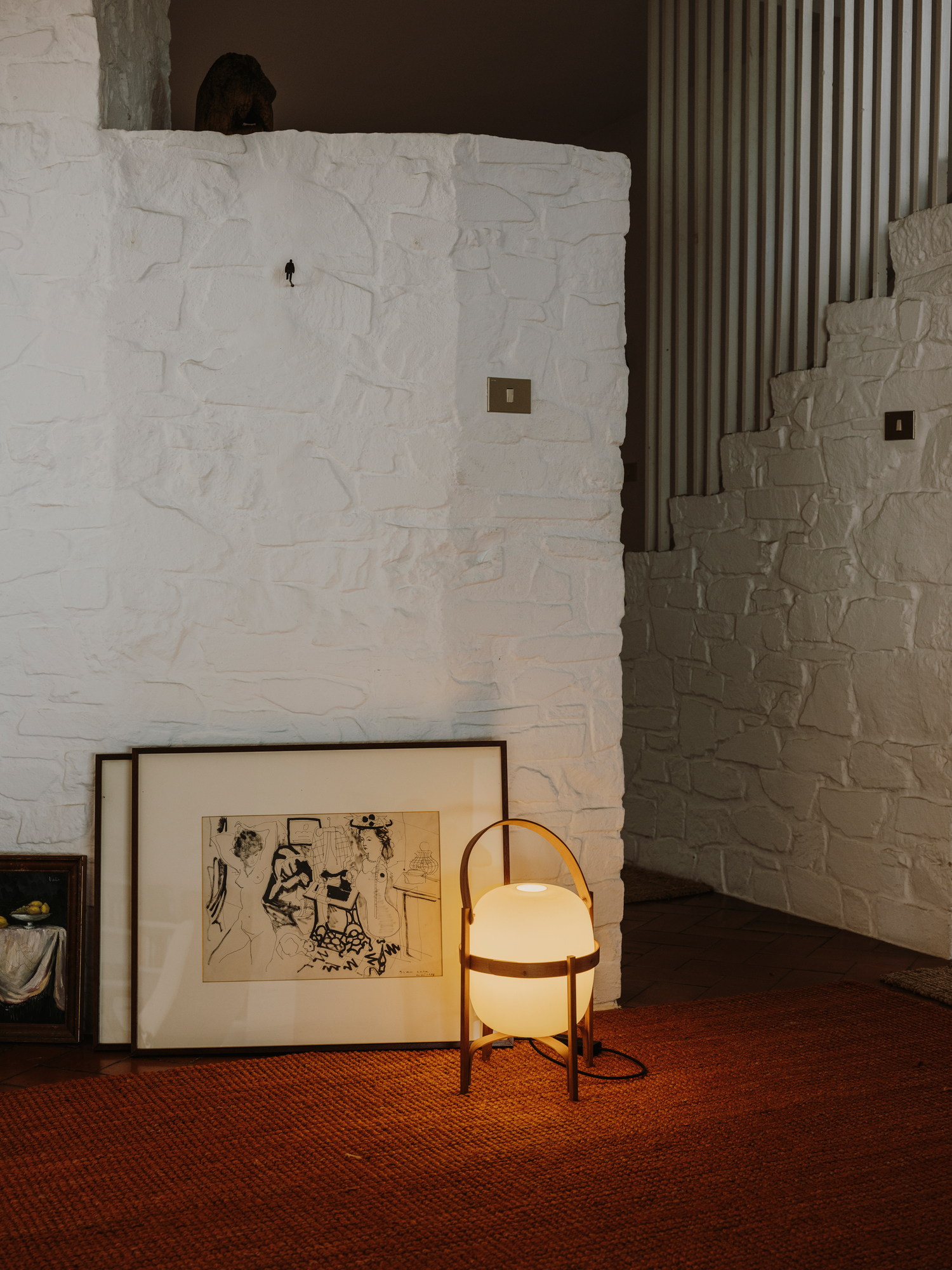 Cesta Tischleuchte von Santa & Cole, stimmungsvolle Beleuchtung im Wohnzimmer mit Kunst und Teppich.