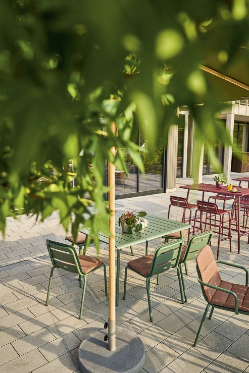 Weishäupl Vapio Sessel und Gartentisch in Grün mit braunen Sitzkissen auf einer Terrasse.