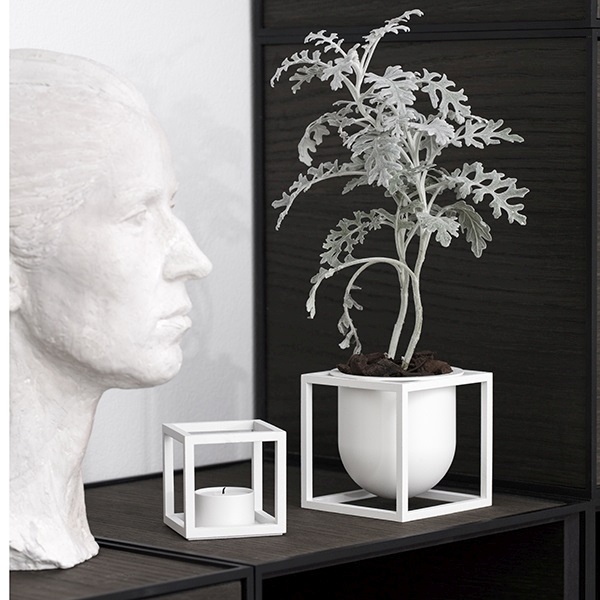 Nahaufnahme des Kubus T Teelichthalters, minimalistisches Design, neben einer Skulptur und einer Pflanze.