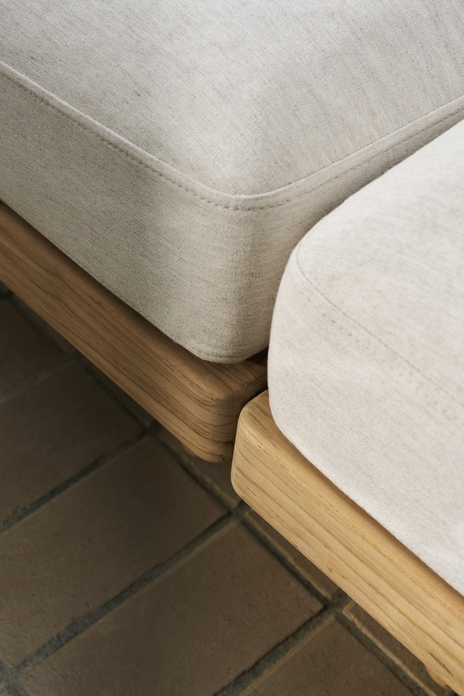 Detailaufnahme von zwei E511 Embrace Outdoor Sofa Modulen mit hellen Polstern und Holzrahmen.