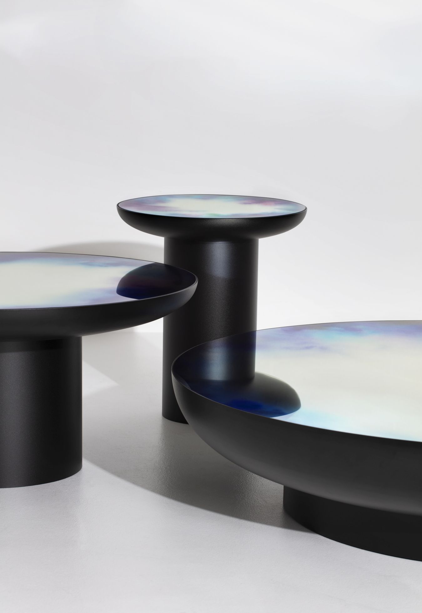 Drei moderne, schwarze Couchtische mit farbigen, reflektierenden Oberflächen für Wohnzimmer und Lounge.
