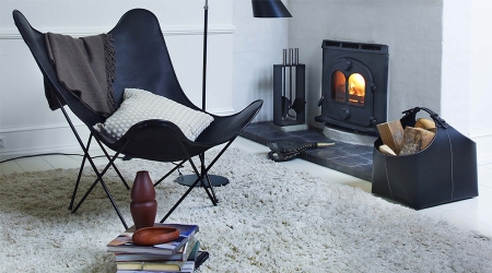 Schwarzer Butterfly Chair Sessel aus Leder vor Kamin, gemütliches Wohnzimmer mit Teppich.