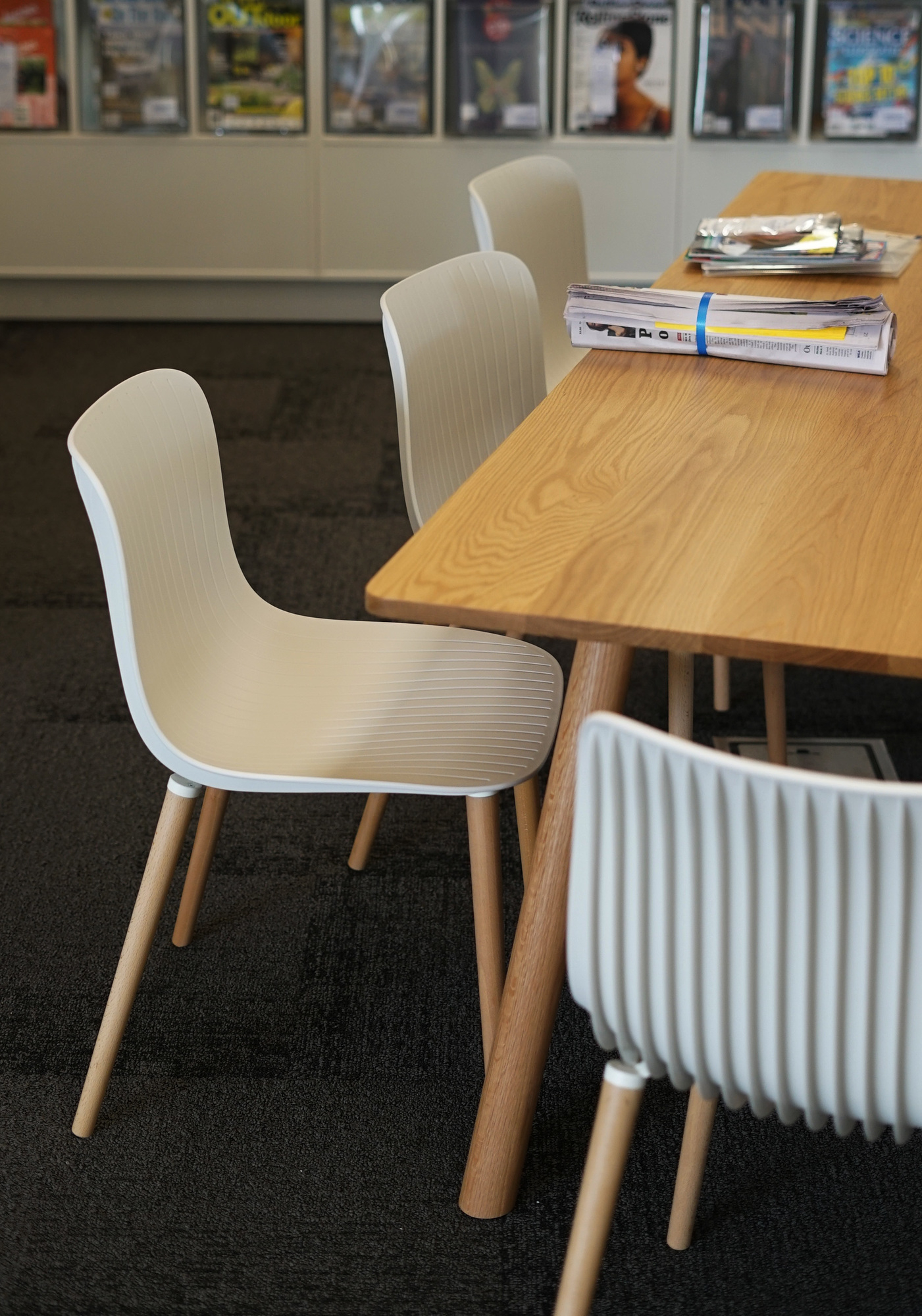 Nahaufnahme von Dragonfly Stühlen mit Holzbeinen an einem Holztisch. Moderne Sitzmöbel für Büro oder Zuhause.