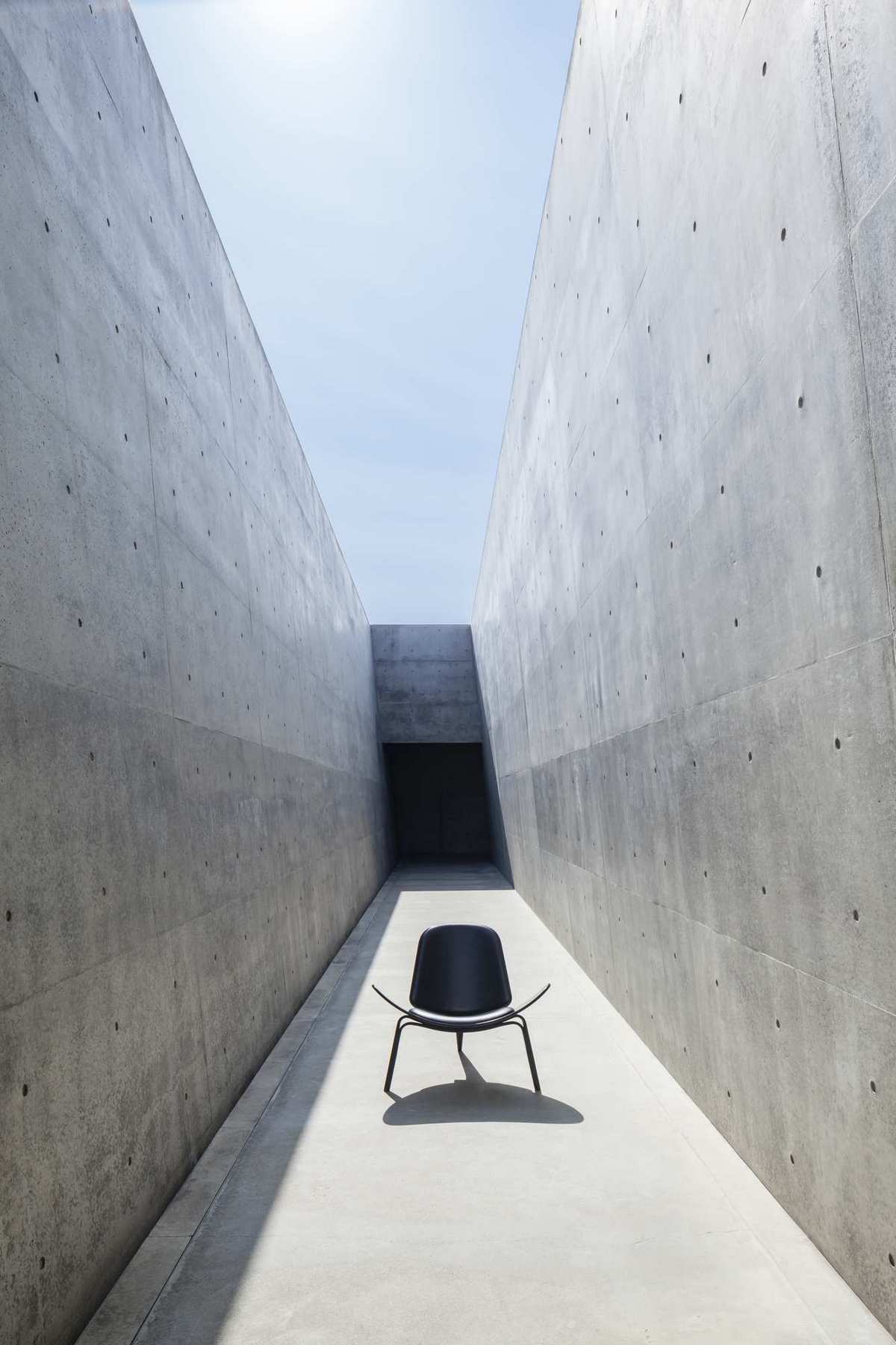 Schwarzer CH07 Shell Chair Stuhl von Carl Hansen & Søn in minimalistischer Betonumgebung. Designklassiker.