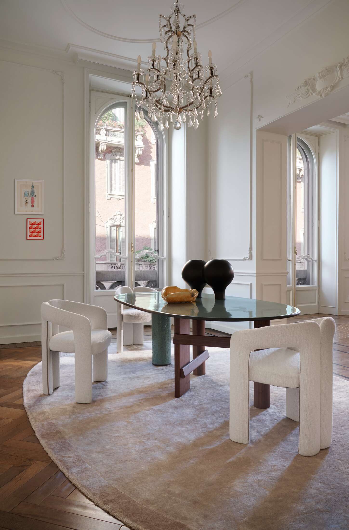 Innenaufnahme mit Cassina 562 Dudet Sessel in Weiß um einen Esstisch mit Glasplatte und Dekoration.
