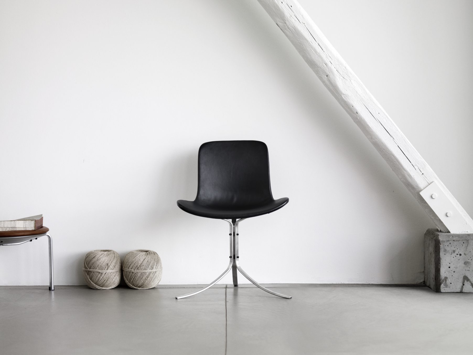 Schwarzer PK9 Stuhl von Fritz Hansen mit Lederbezug und filigranem Metallfuß vor weißer Wand.