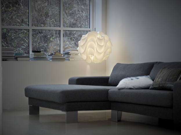 Weiße Model 172 Le Klint Pendelleuchte im Wohnzimmer über einem grauen Sofa.