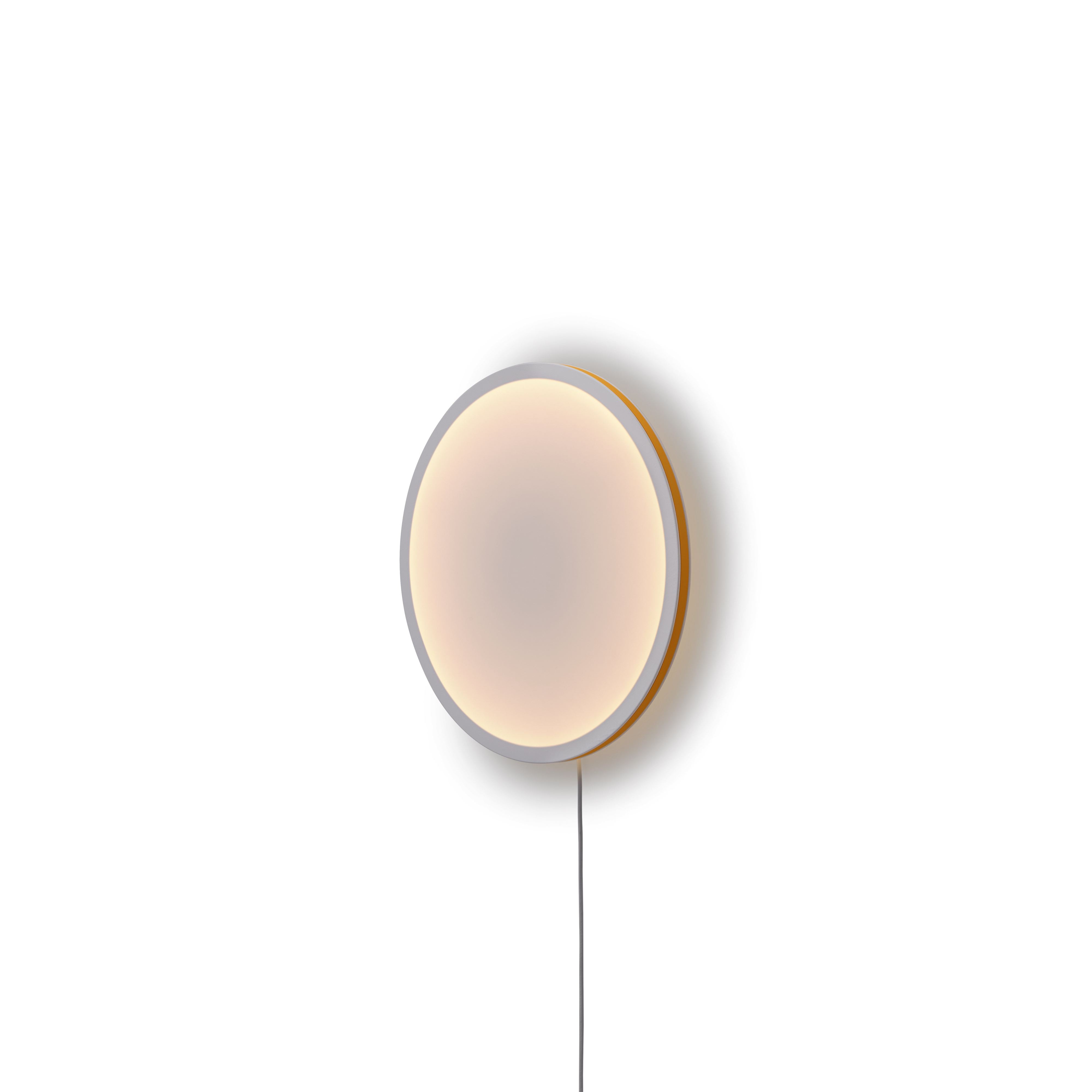 Nahaufnahme der runden Muuto Calm Wall Lamp Wandleuchte mit warmem Licht und Kabel.