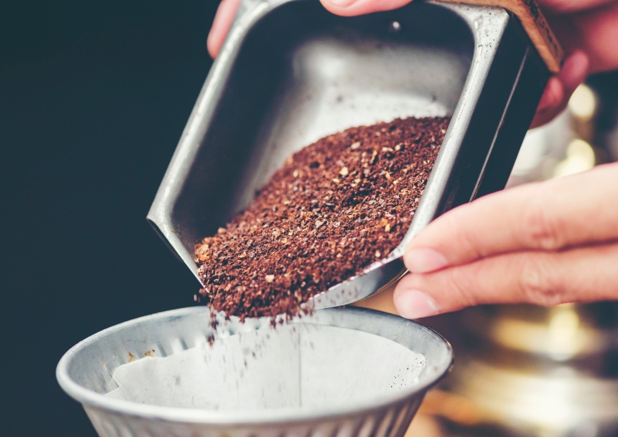 Gemahlener Kaffee wird in einen Kaffeefilter für die Zubereitung von Filterkaffee gegossen.