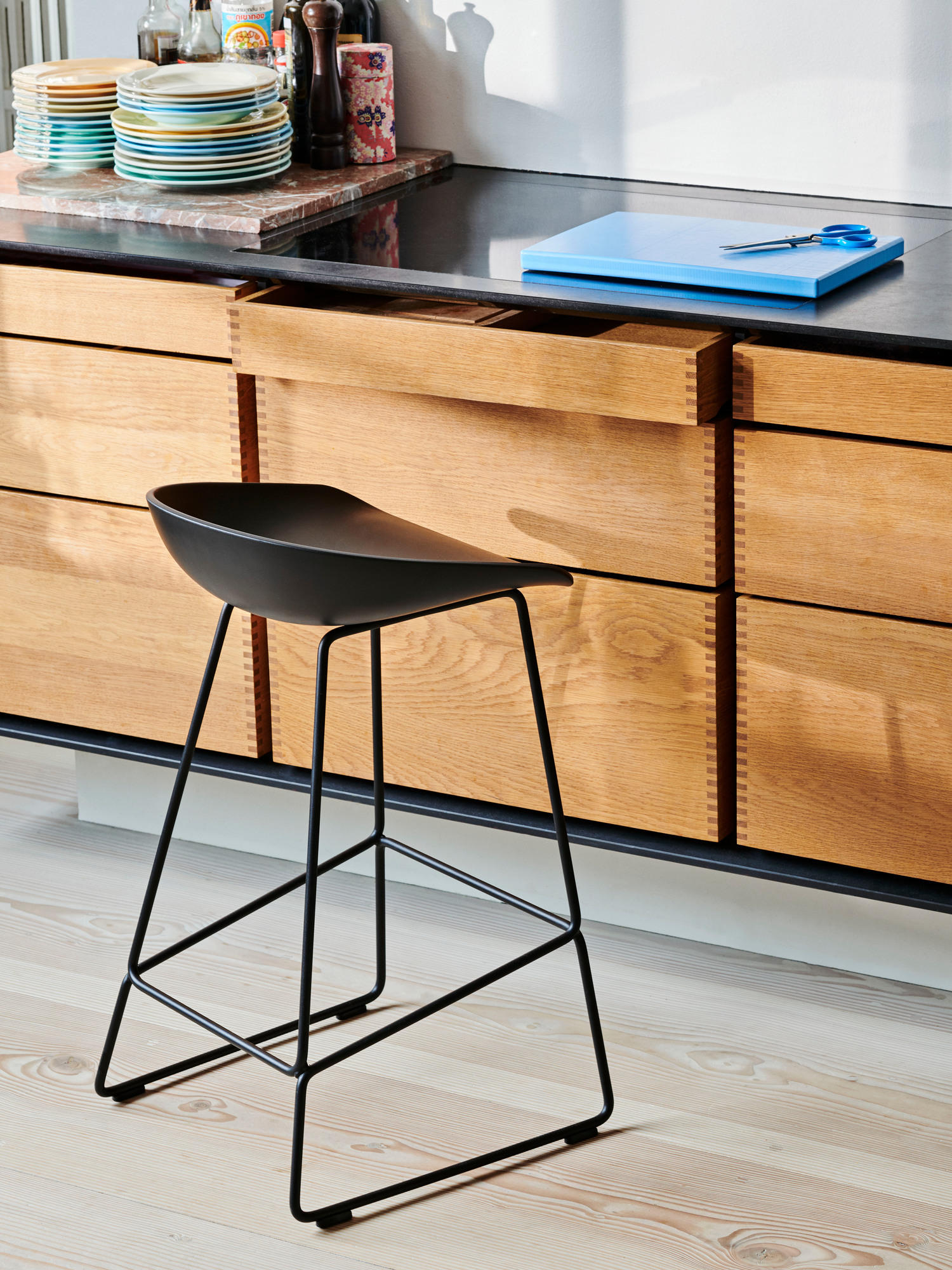 Schwarzer About a Stool AAS 38 Barhocker von Hay vor einer modernen Küchenzeile mit Holzschubladen.
