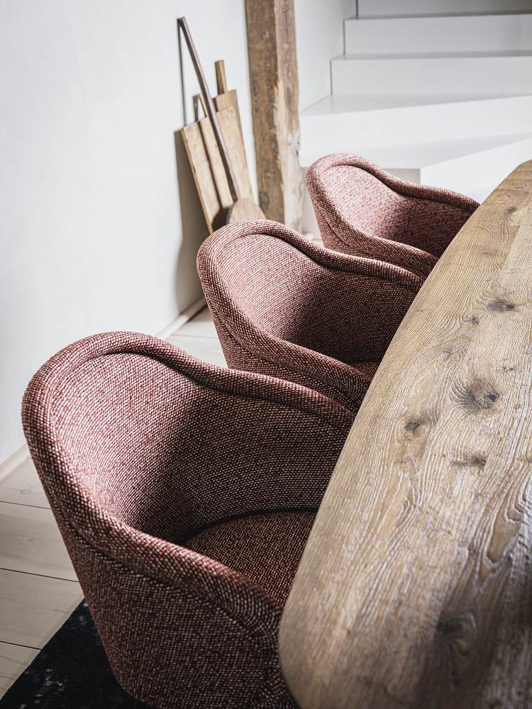 Ona Armlehnstuhl von Freifrau Manufaktur in Rotbraun am Holztisch, elegante Sitzmöbel für Esszimmer.