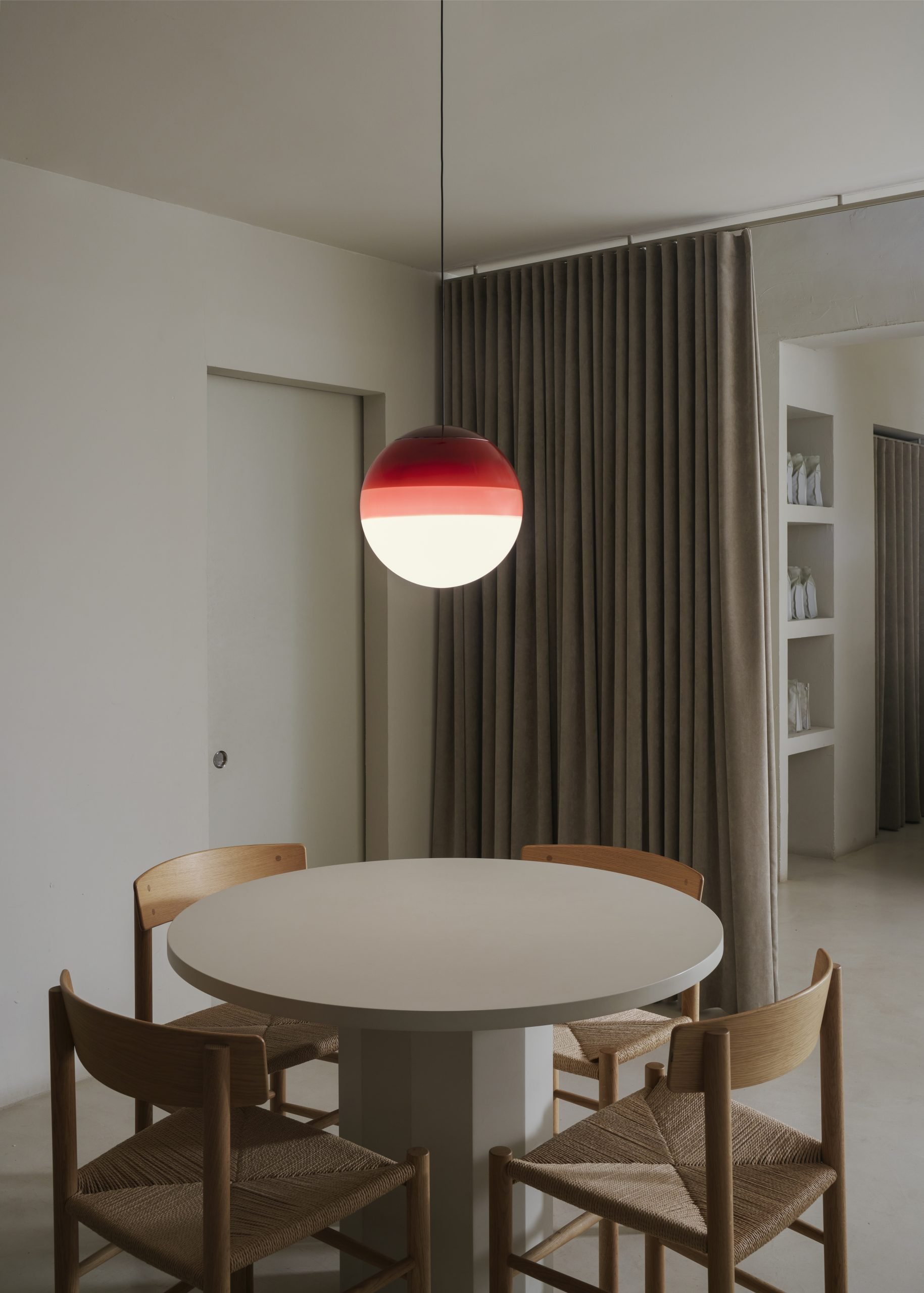 Dipping Light Pendelleuchte von Marset in Rot-Weiß über Esstisch mit Stühlen.