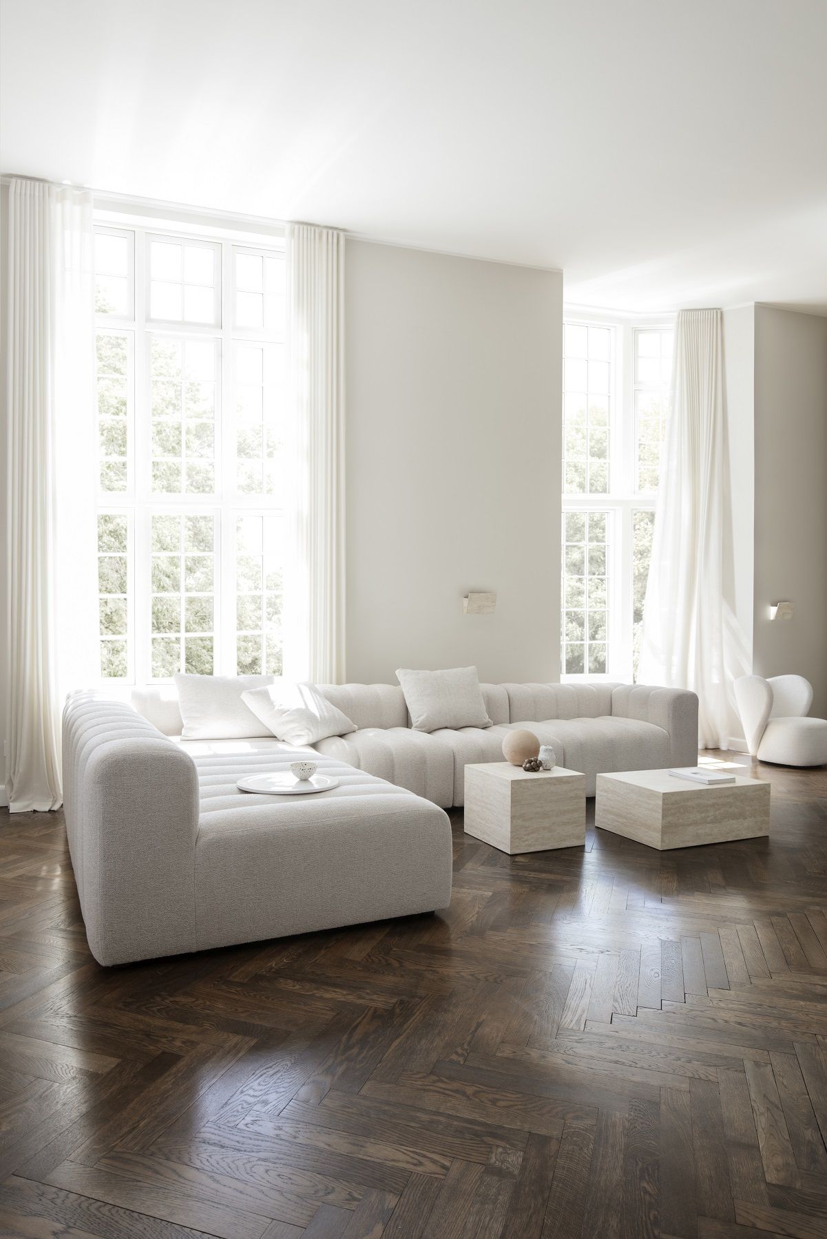 Helles Wohnzimmer mit NORR11 Cubism Table Large Tisch und modularem Sofa auf dunklem Fischgrätparkett.