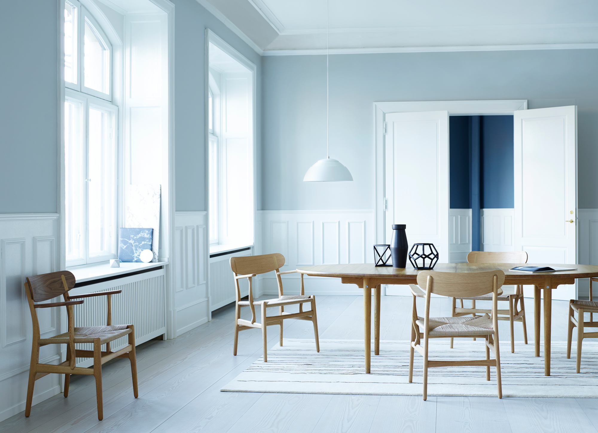 Esszimmer mit rundem Holztisch und mehreren CH26 Stühlen von Carl Hansen mit geflochtenen Sitzen.