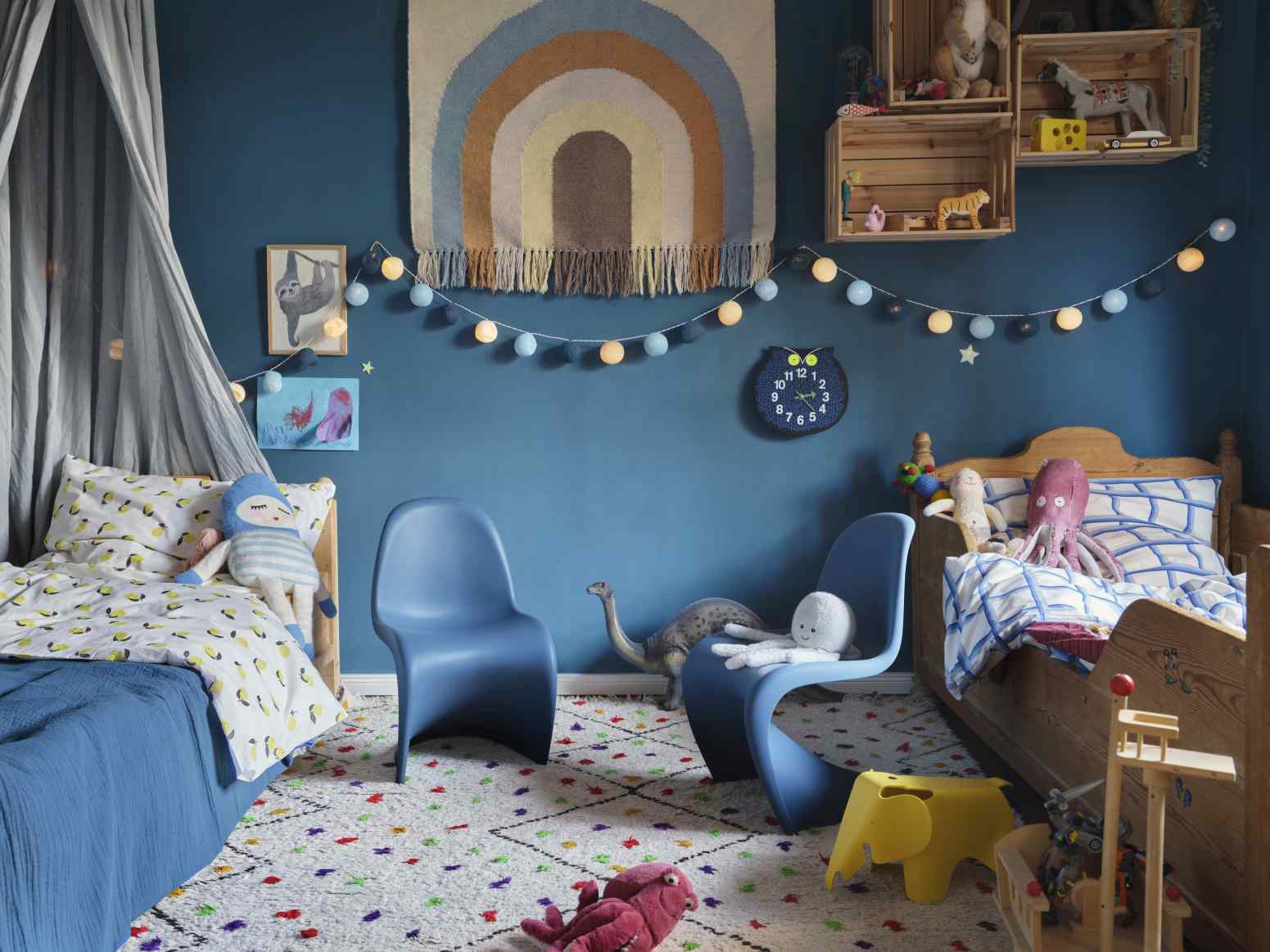 Kinderzimmer mit blauen Wänden, Betten, Stühlen und der Omar the Owl Zoo Timers Wanduhr von Vitra.