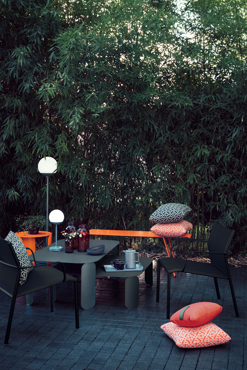 Schwarzer Cadiz Outdoor Stuhl von Fermob an Esstisch im Garten mit Bambushintergrund.