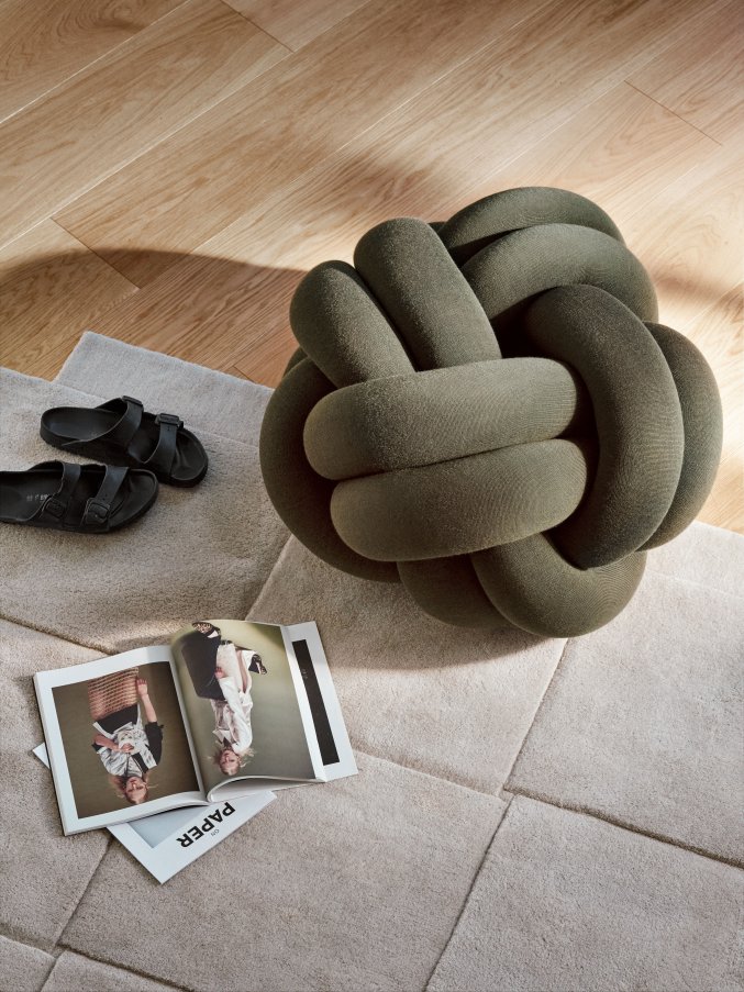 Nahaufnahme: Grünes Knot Kissen von Design House Stockholm auf beigem Teppich.
