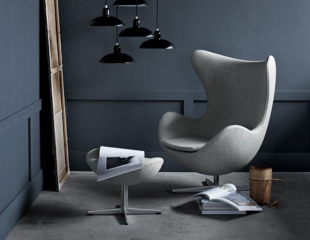 Grauer Egg Chair Sessel mit Fußhocker und schwarzen Pendelleuchten im modernen Wohnzimmer. Designmöbel für stilvolles Wohnen.