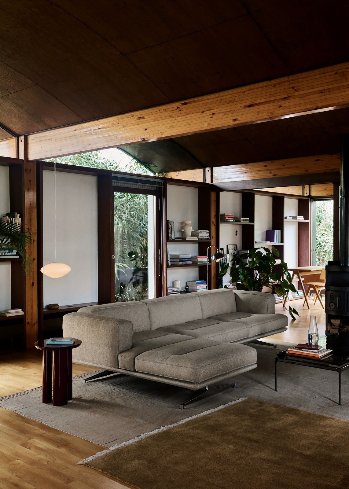 Beiges Inland Sofa von AndTradition im Wohnzimmer mit Holzdecke und Bücherregalen.
