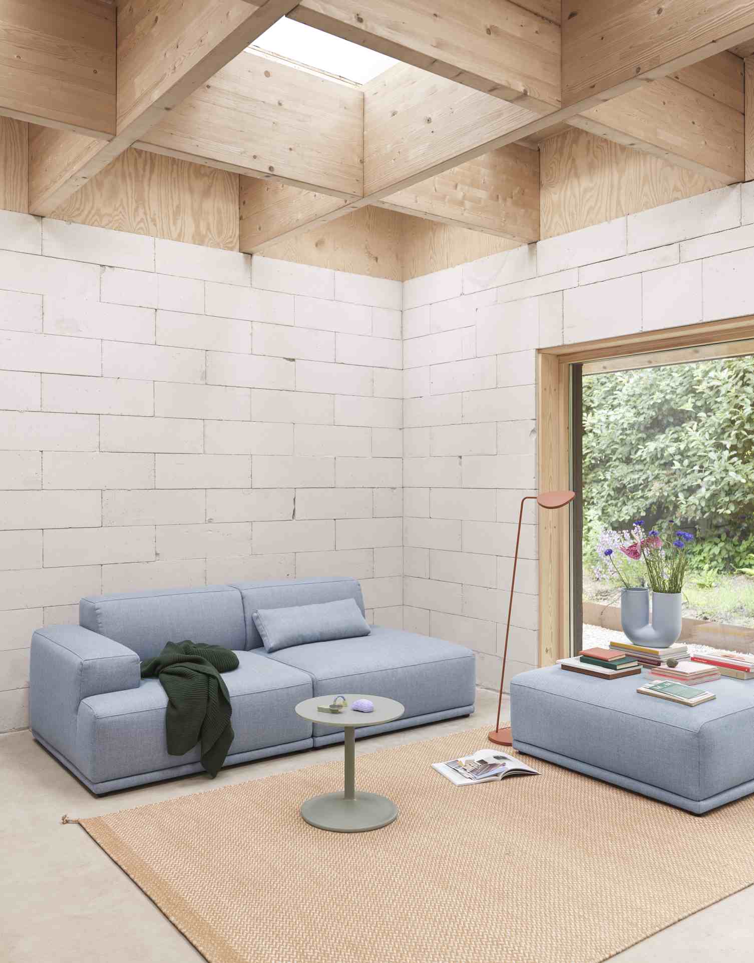 Helles Wohnzimmer mit blauem Connect Soft Sofa, Beistelltisch und passendem Hocker von Muuto.