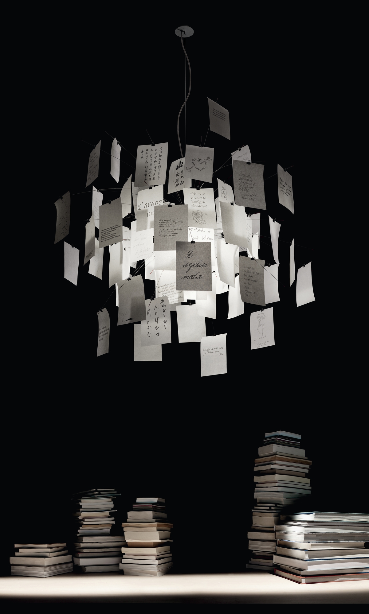 Zettel'z 5 Hängeleuchte von Ingo Maurer, moderne Designerlampe mit beschrifteten Zetteln, Bücherstapel im Vordergrund, stimmungsvolle Beleuchtung.