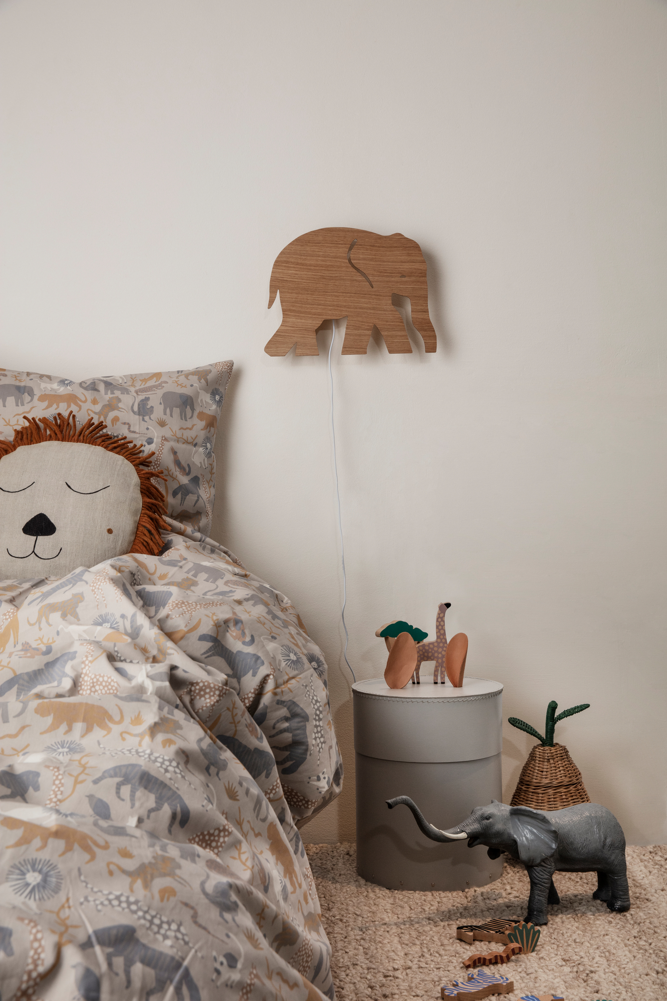 Kinderzimmer-Szene mit Ferm Living Aufbewahrungskorb (ähnlich Birne) neben Bett mit Tiermotiven und Holzspielzeug.