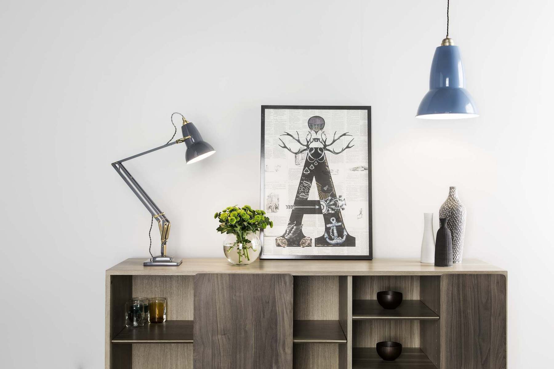 Graue Original 1227 Anglepoise Tischleuchte aus Messing auf einem Sideboard mit Dekoration und Lampe.