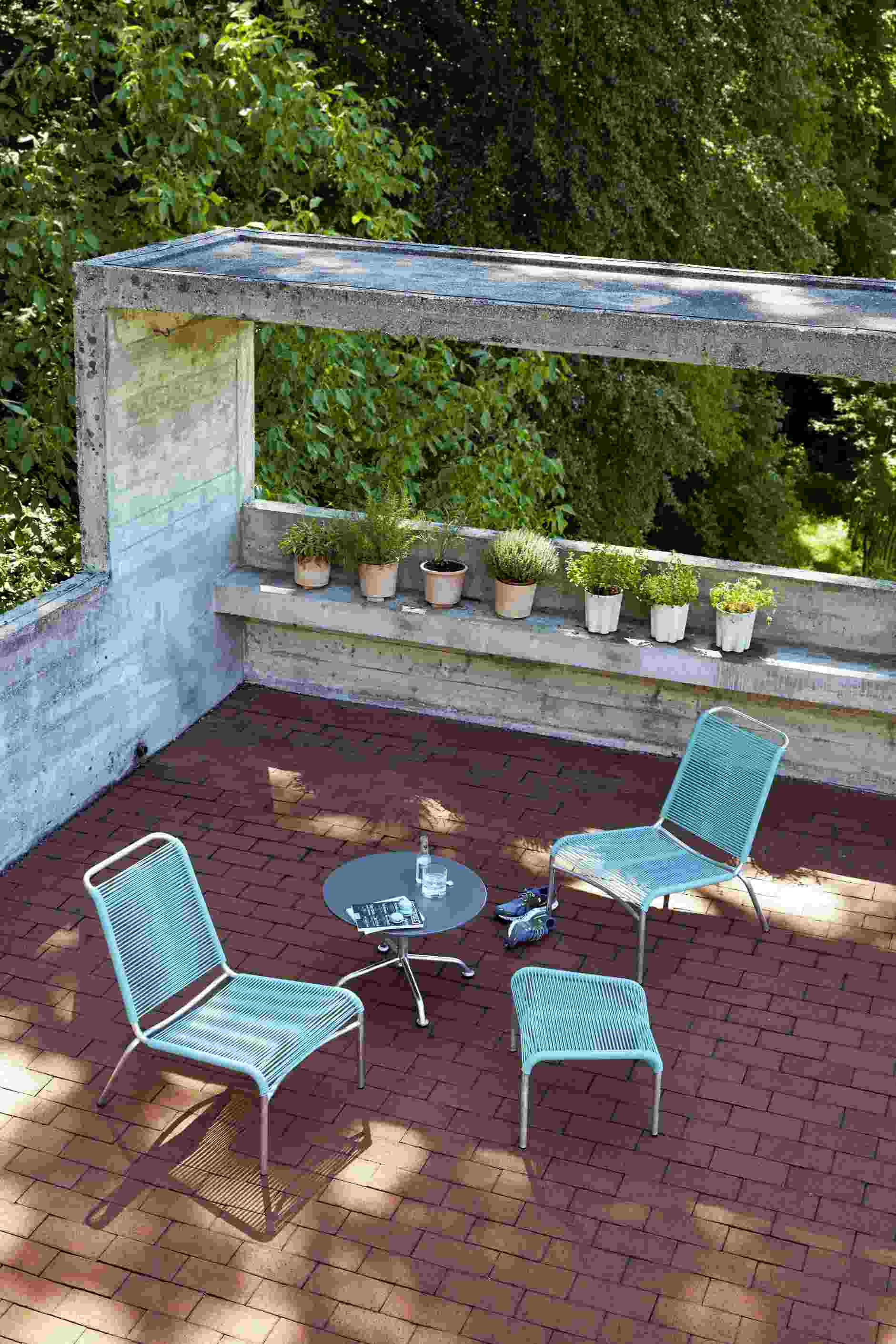 Altorfer Lounge Stuhl Outdoor Embru: Zwei blaue Lounge Stühle und Hocker auf einer Terrasse.