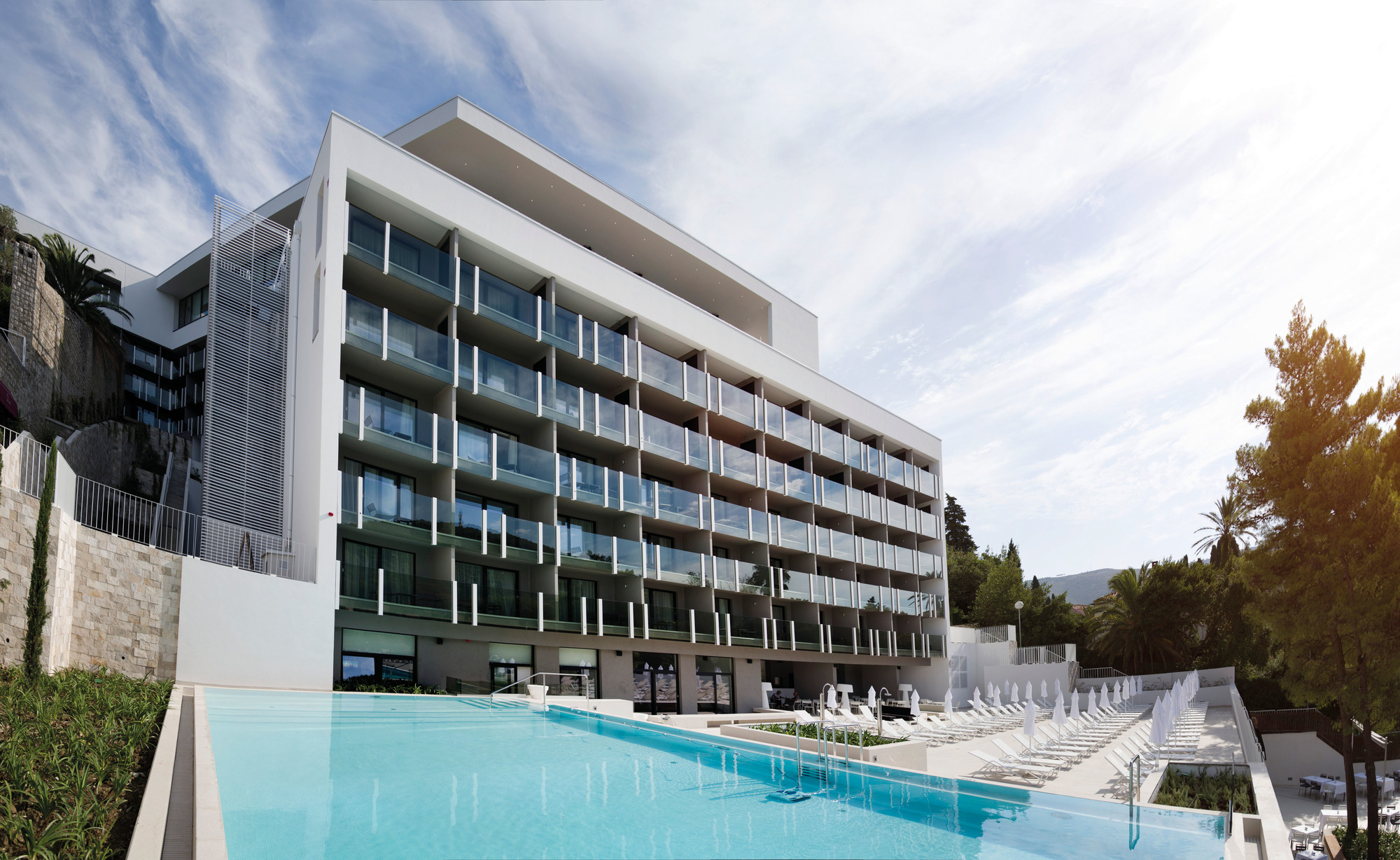 Luxuriöses Hotel mit Pool und weißen Emu Sonnenliegen für entspannte Stunden im Freien.