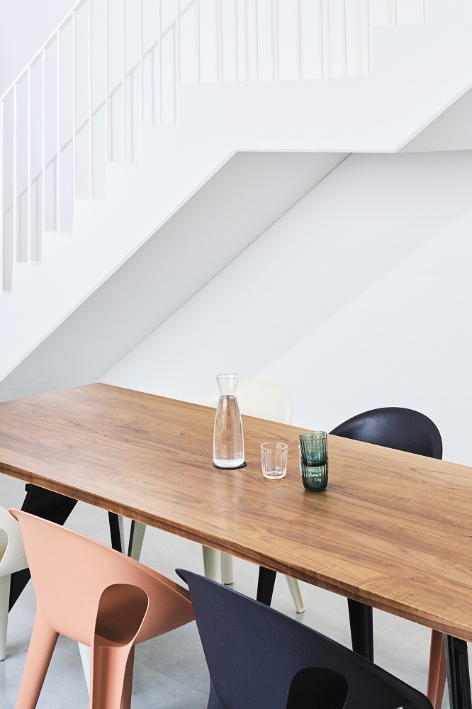 Detailaufnahme von Magis Bell Stühlen in verschiedenen Farben um einen Holztisch, minimalistisches Design für Indoor und Outdoor.