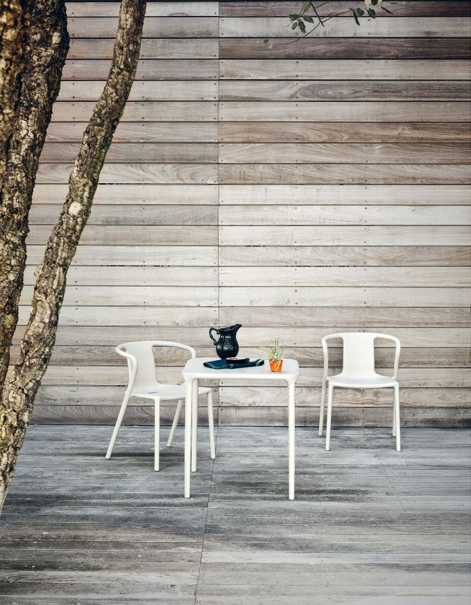 Weißer Air Table von Magis mit zwei Stühlen im Außenbereich vor Holzwand.