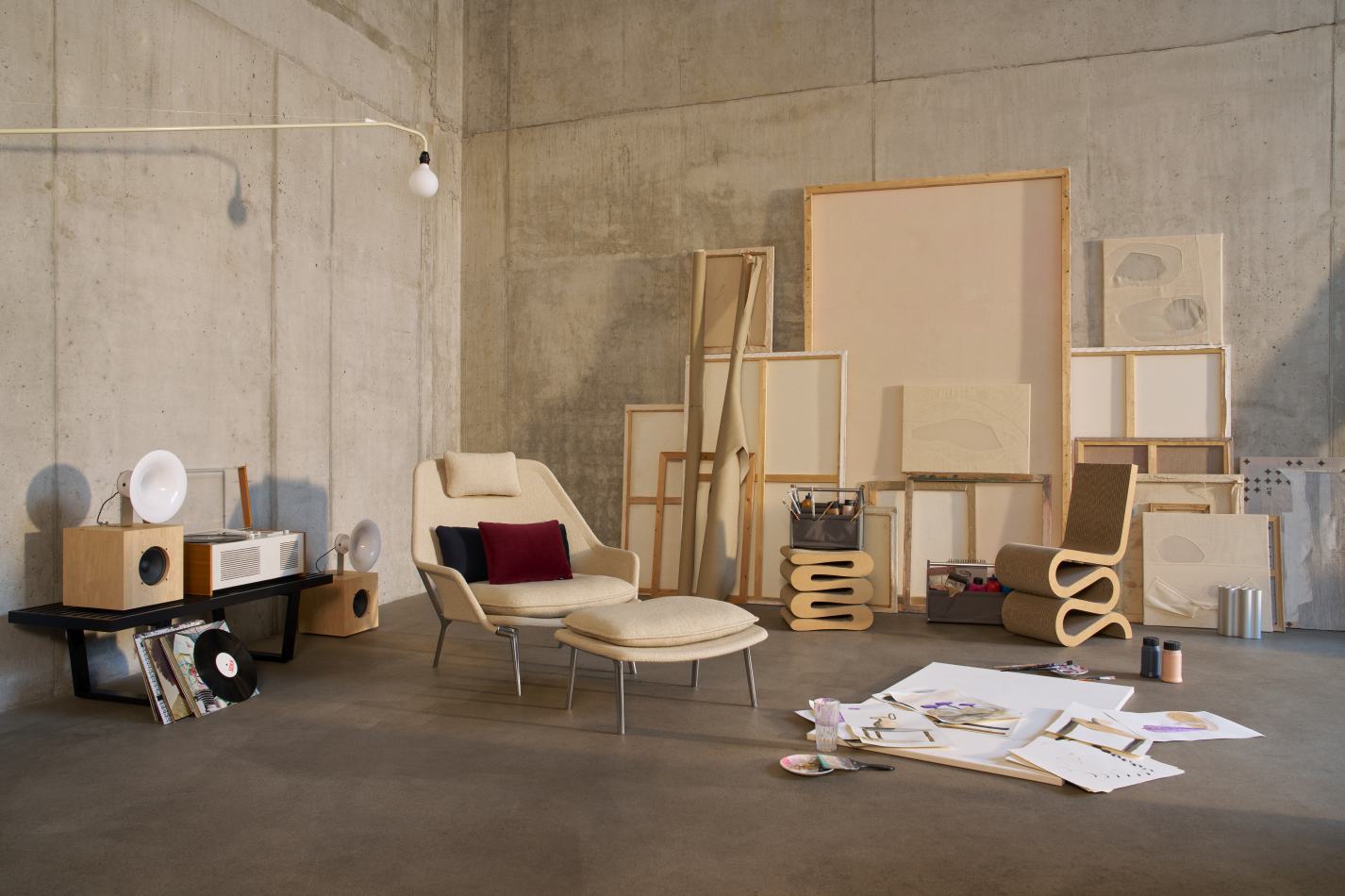 Slow Chair Sessel Stoff Vitra in beigem Stoffbezug mit Hocker in Kunstatelier-Umgebung.