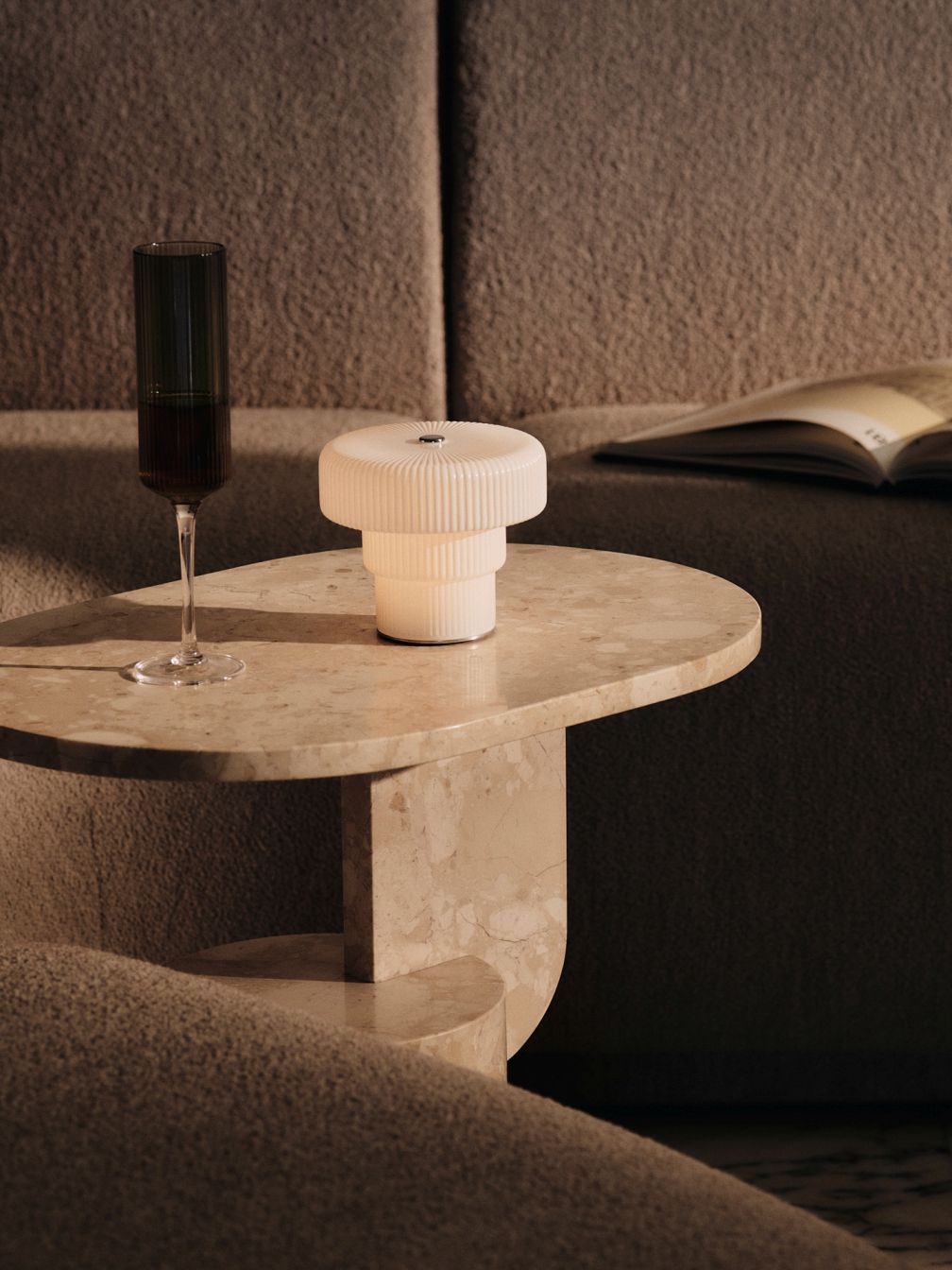 Nahaufnahme der Ferm Living Ripple Tischleuchte auf einem Marmortisch mit Weinglas und Buch.